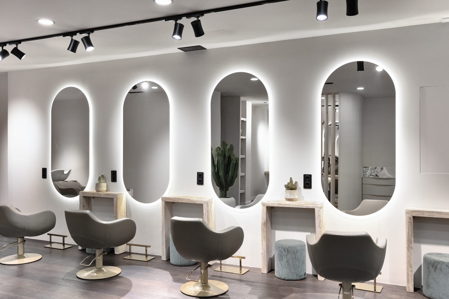 Zona de tocadores con espejos iluminados y sillones grises en peluquería Mataró La Están Peinando